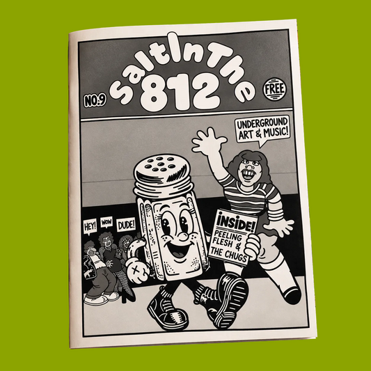 A printed magazine or zine titled "Salt in the 812" lies on a distressed, rusted metal surface. The cover is black and white with cartoon-style artwork featuring a salt shaker and a person holding an "Inside!" sign.